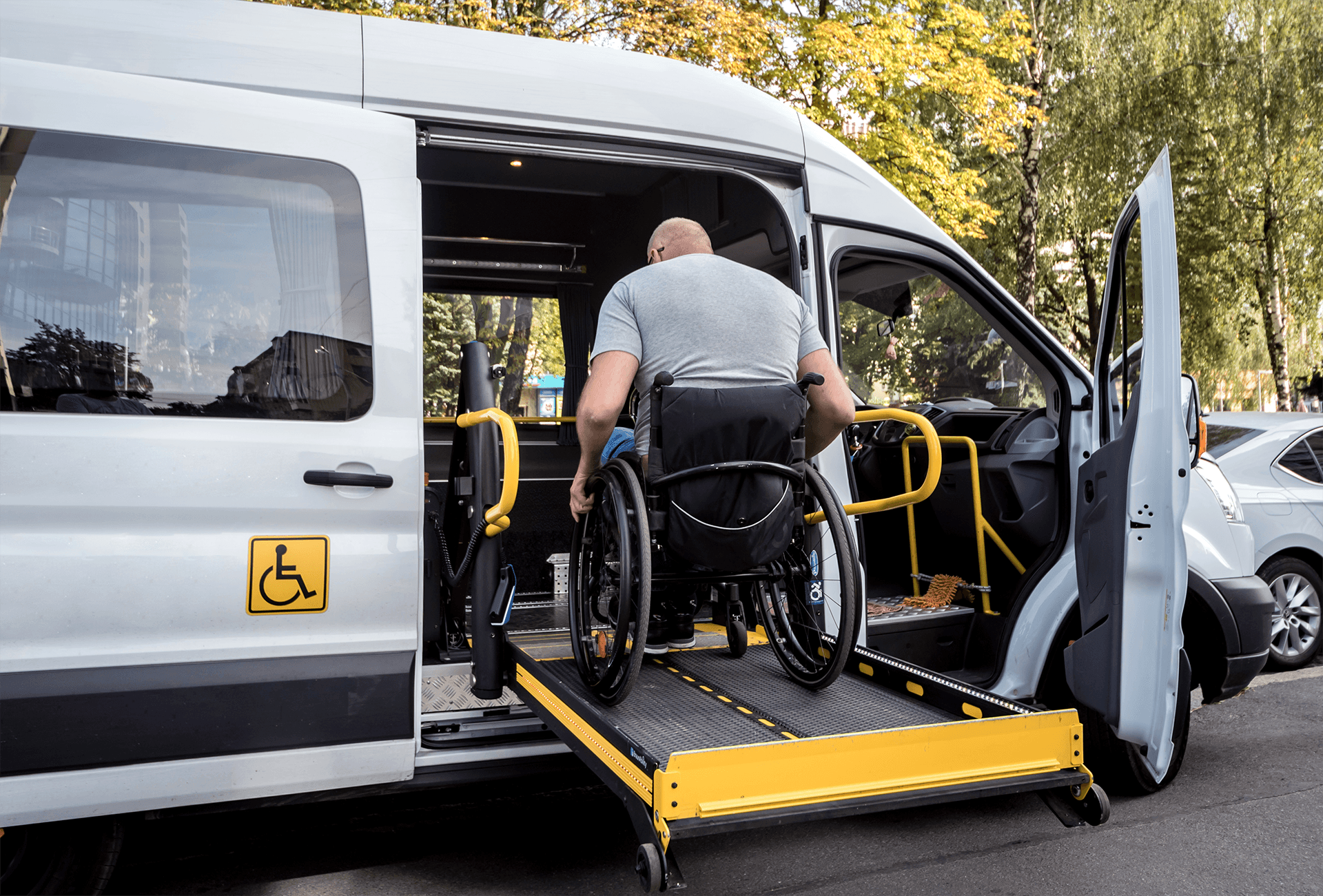 Passenger in a wheelchair boarding an accessible transport van using a ramp lift